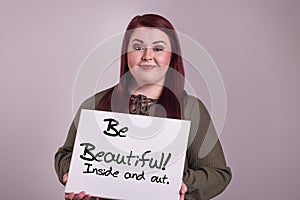 Beautiful young woman presenting a sign with Be Beautiful Inside and out painted on whiteboard