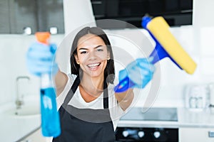 Beautiful young woman in protective gloves cleaning kitchen cabinet