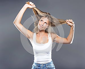 Beautiful young woman pulling her hair over gray background.