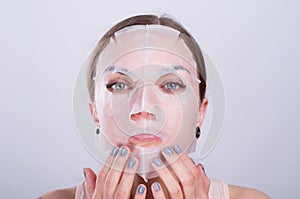 Beautiful young woman puts anti-aging mask on her face.