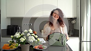 Beautiful young woman puts the lunch box in bag getting ready to go to work