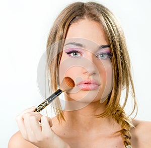 Beautiful young woman putting on makeup