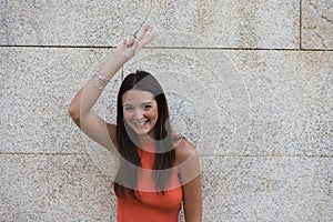 beautiful young woman raises her arms with clenched fists celebrating victory and achievements on gray background