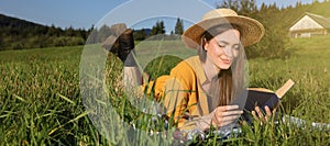 Beautiful young woman reading book on green meadow. Banner design