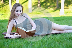 Beautiful young woman reading book at park