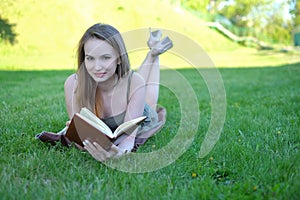 Beautiful young woman reading book at park