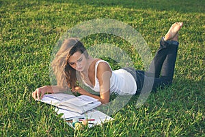 Beautiful young woman reading on a green meadow