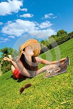 Beautiful young woman reading magazine in the park