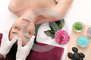 Beautiful young woman receiving facial massage in spa salon