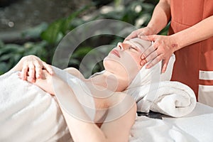 Beautiful young woman receiving head massage relaxing in spa salon