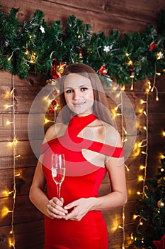 Beautiful young woman in red dress with glass of champagne. New Year`s party.