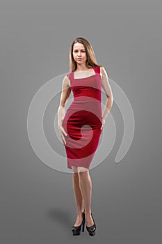 Beautiful young woman in a red dress on a gray background