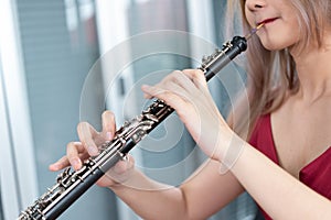 Beautiful young woman in a red dress playing the clarinet .,Classical musician oboe playing