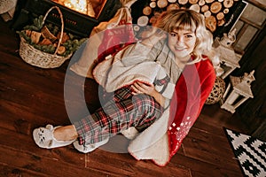 A beautiful young woman in a red plaid sits in warm classic New Year interior