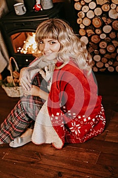 A beautiful young woman in a red plaid sits in warm classic New Year interior