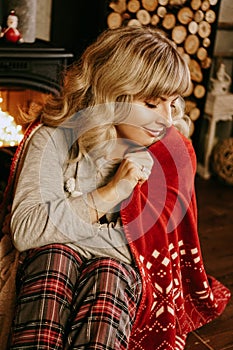 A beautiful young woman in a red plaid sits in warm classic New Year interior