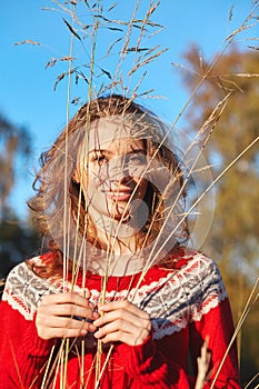 Beautiful young woman in red sweater in park