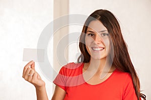 Beautiful young woman in red t shirt holds blank card over white background