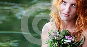 Beautiful young woman, redhead bride, with red hair, sits eagerly abandoned with a bouquet of flowers in a boat and waits full of