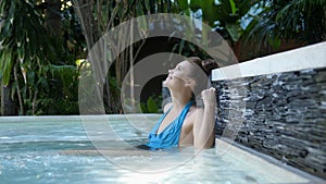 Beautiful young woman relaxes in a hydromassage jacuzzi, in swimming pool. Concept: spa procedures, body massages, spa