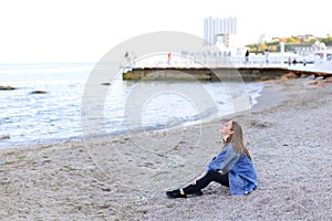 Beautiful young woman relaxes sitting on beach and enjoys view o