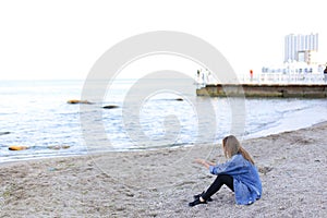 Beautiful young woman relaxes sitting on beach and enjoys view o