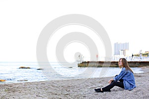 Beautiful young woman relaxes sitting on beach and enjoys view o