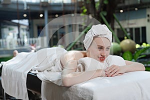 Beautiful young woman relaxes on a spa bed surrounded by nature. Tranquility
