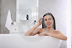 Beautiful young woman relaxing in bathtub at home