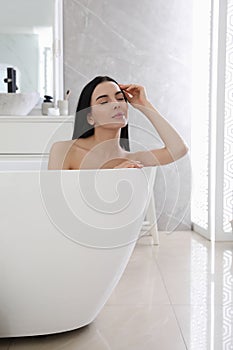 Beautiful young woman relaxing in bathtub at home