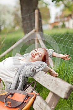 Beautiful young woman relaxing on a bench outside in rural environment