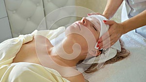 Beautiful young woman relaxing with face massage at luxury spa salon, close-up.