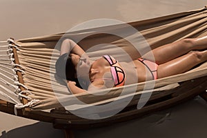 Beautiful young woman relaxing on hammock at beach