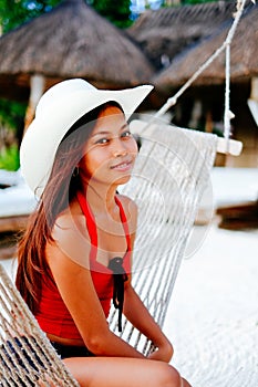 Beautiful young woman relaxing on hammock on the white sand beach during travel vacation