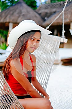 Beautiful young woman relaxing on hammock on the white sand beach during travel vacation