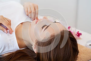 Beautiful young woman relaxing with hand massage at beauty spa salon.