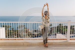 Beautiful young woman relaxing, having fun, enjoy view on sea, ocean on the balcony, terrace. Girl, tourist on vacation