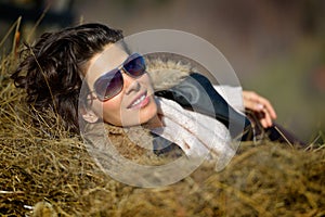 Beautiful young woman relaxing on hay stack