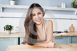 Beautiful young woman relaxing at the kitchen. Happy smiling girl home portrait.