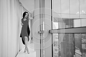 Beautiful young woman relaxing looking out window. Black white image