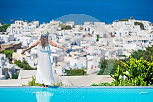 Beautiful young woman relaxing near pool with amazing view on Mykonos, Greece