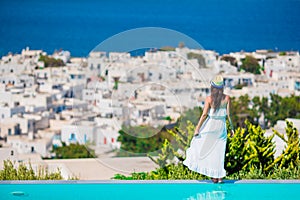 Beautiful young woman relaxing near pool with amazing view on Mykonos, Greece