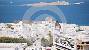 Beautiful young woman relaxing near pool with book in rich hotel with amazing view on Mykonos, Greece