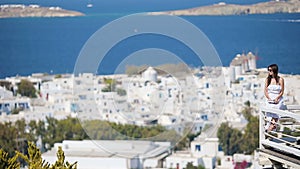 Beautiful young woman relaxing near pool in rich hotel with amazing view on Mykonos, Greece