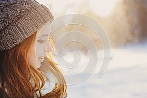 Beautiful young woman relaxing on winter walk in snowy forest, candid capture