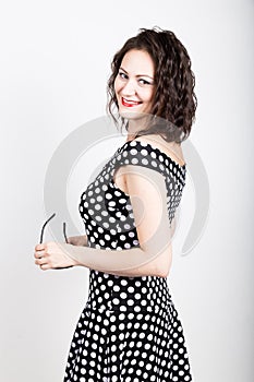 Beautiful young woman removes sun glasses, wears a dress with polka dots. expressing different emotions