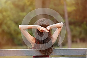 Beautiful young woman resting on bench in park