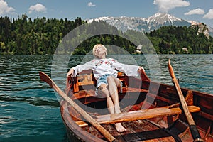 beautiful young woman resting in boat at tranquil mountain lake