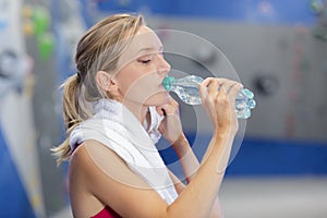 beautiful young woman resting and drinking water in gym