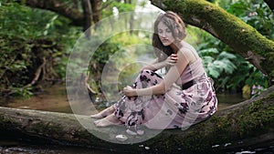 Beautiful young woman resting near the river bank.